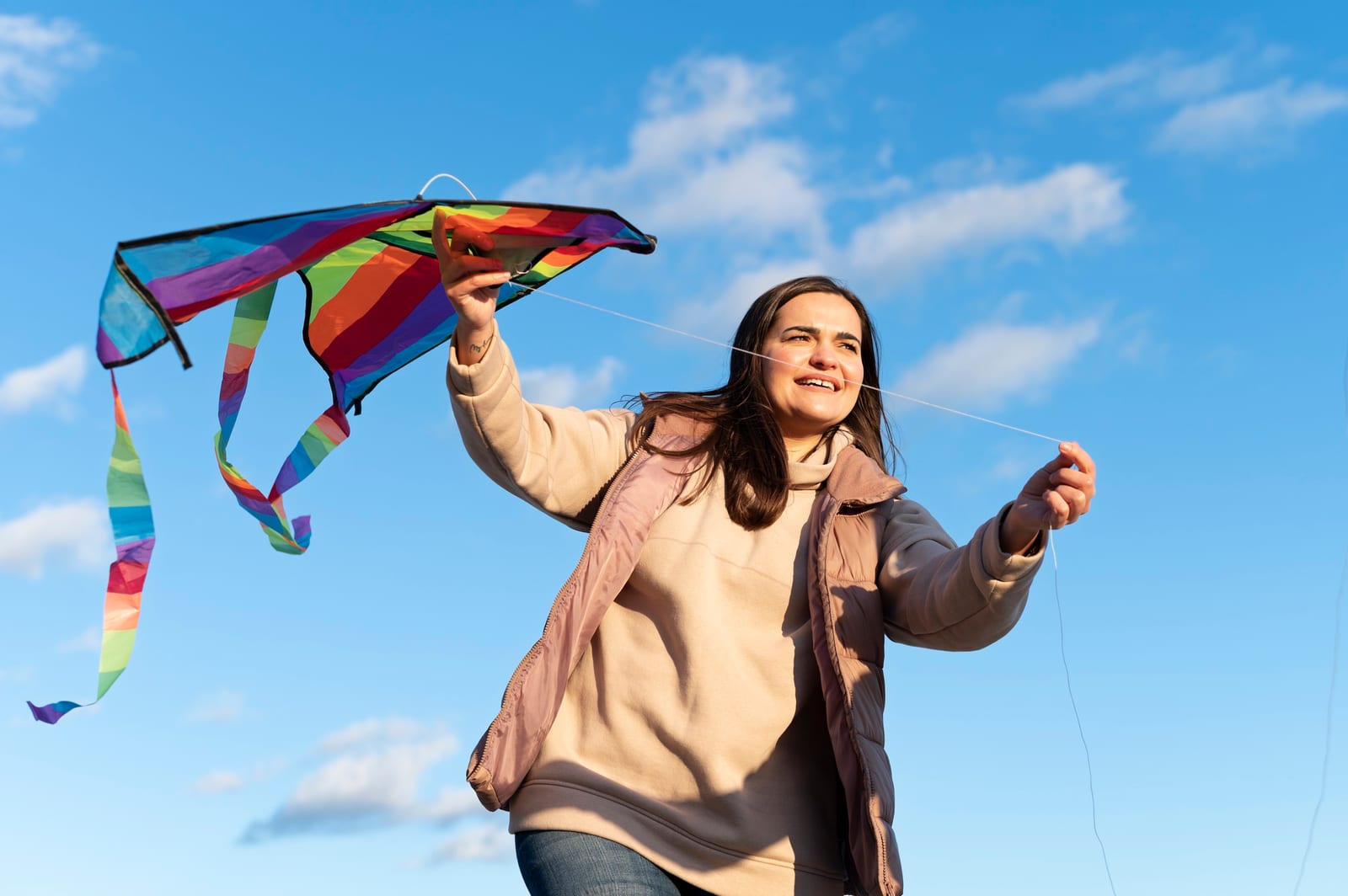 Mulher lança uma pipa colorida contra o céu azul
